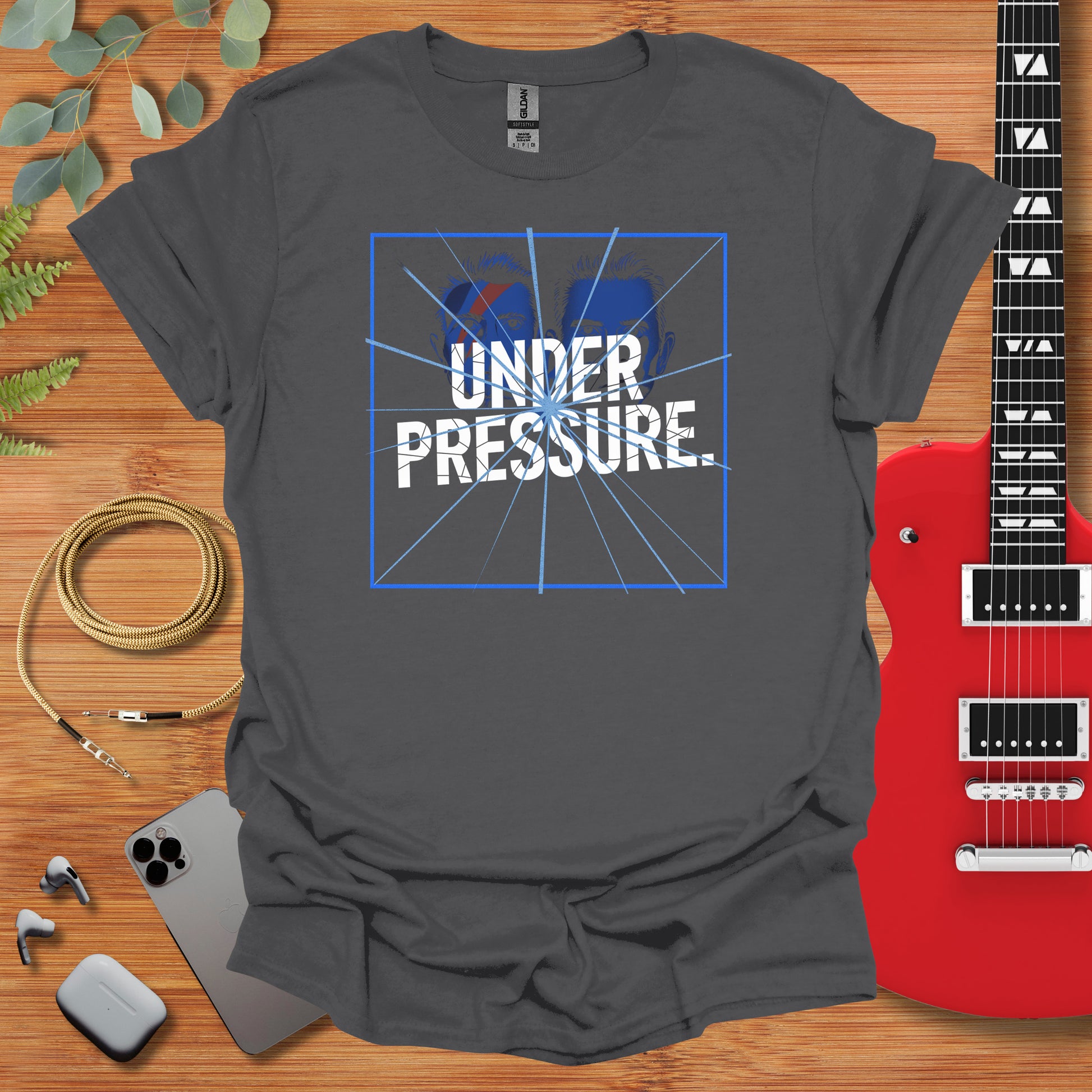 a t - shirt that says under pressure next to a guitar