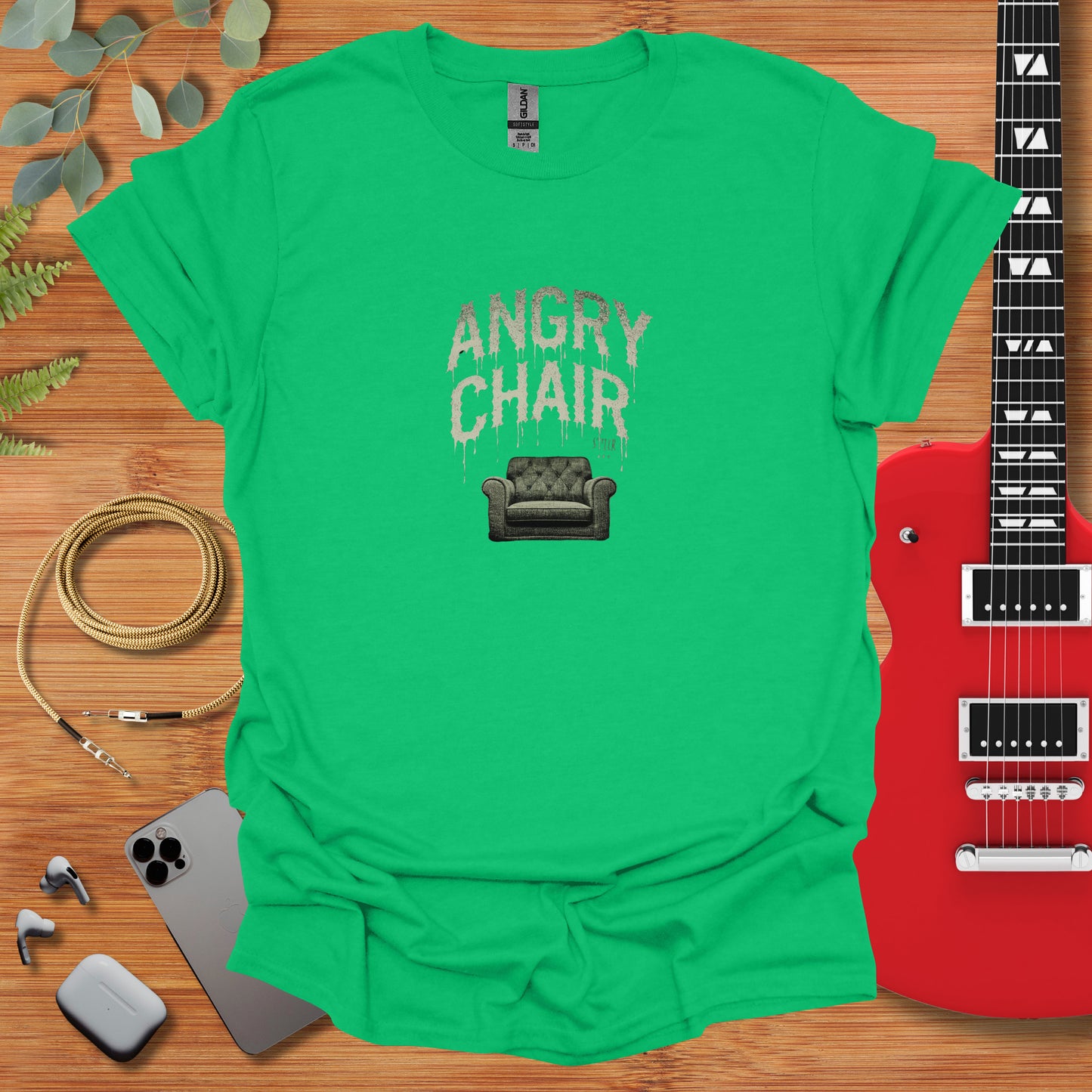 a green t - shirt with the words angry chair on it next to a guitar