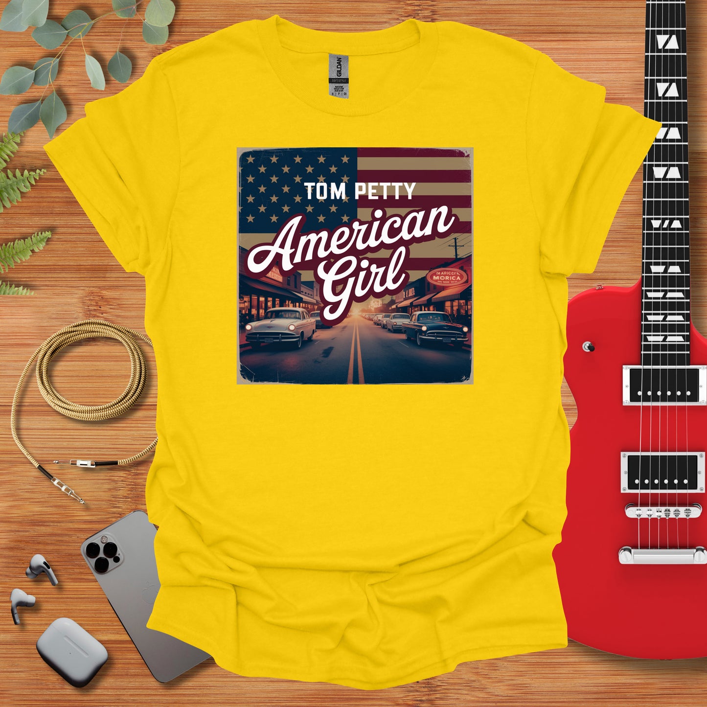 a t - shirt that says tom petty american girl next to a guitar