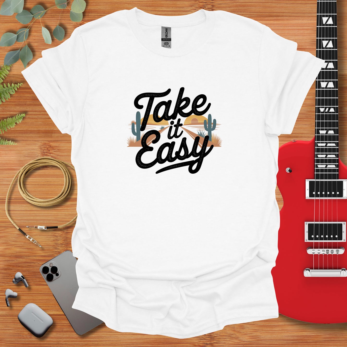 a t - shirt that says take it easy next to a guitar