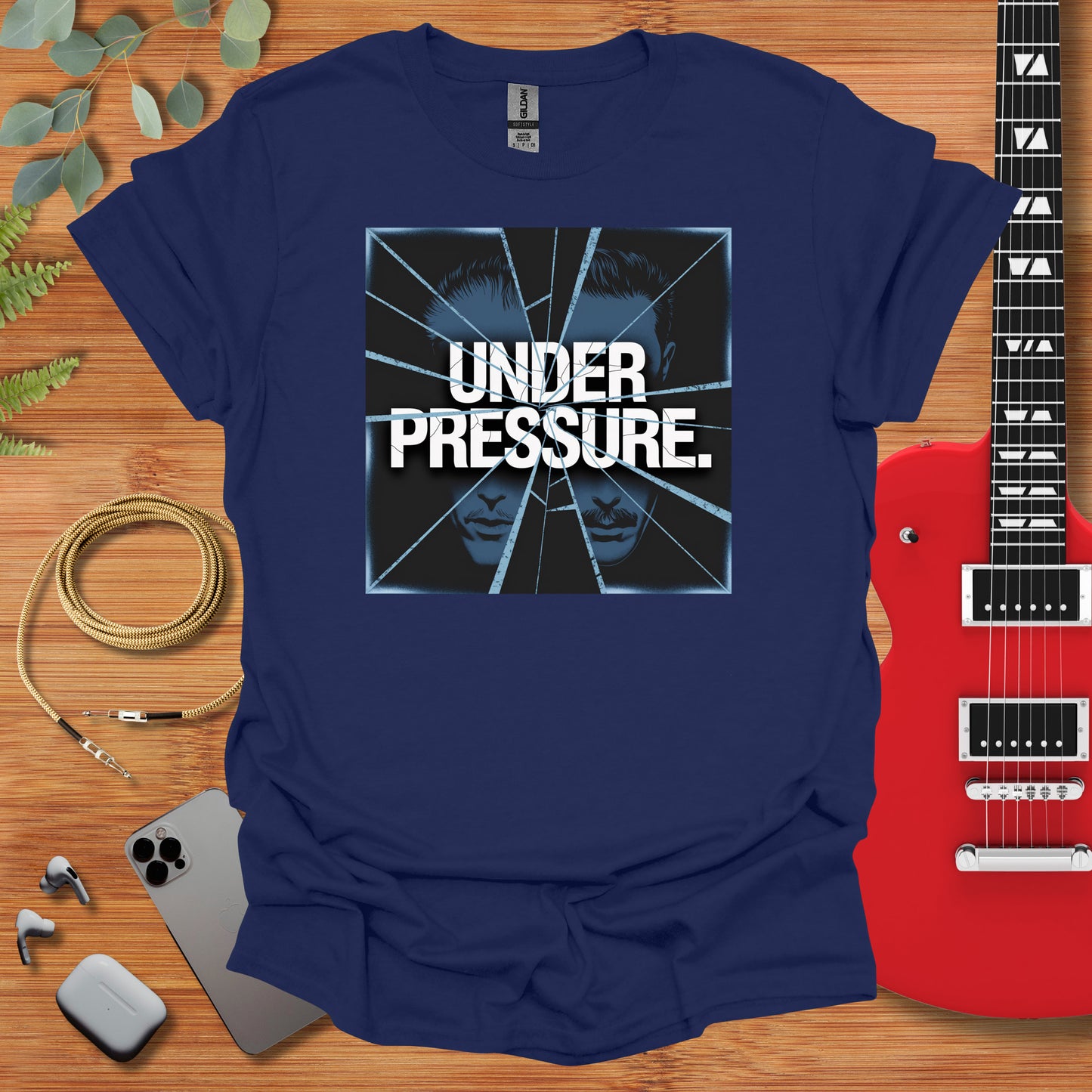 a t - shirt that reads under pressure next to a guitar