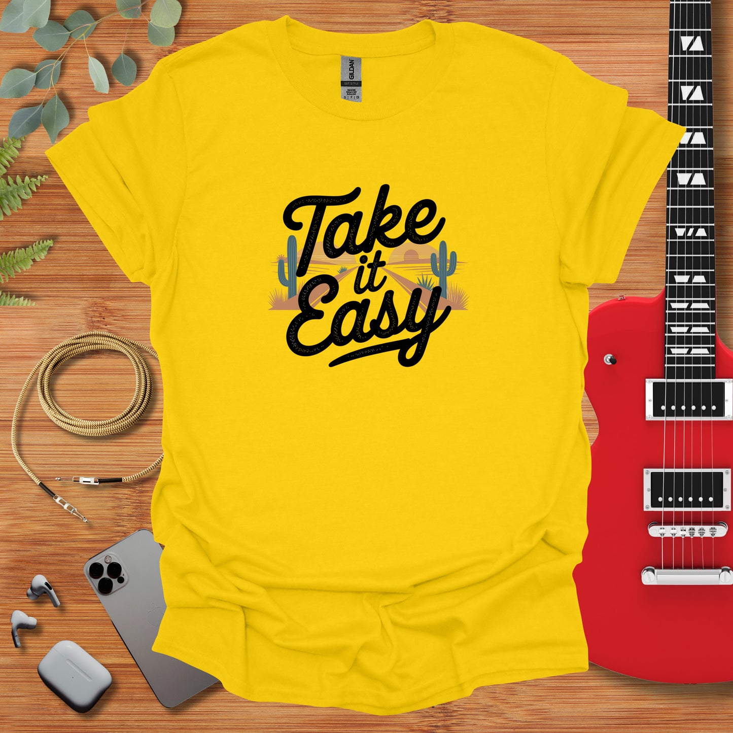 a t - shirt that says take it easy next to a guitar