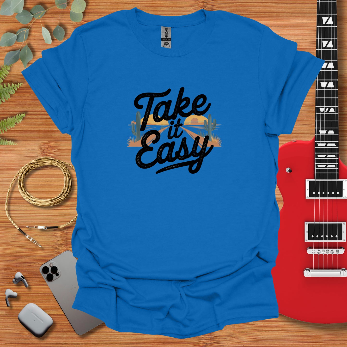 a blue shirt that says take it easy next to a guitar