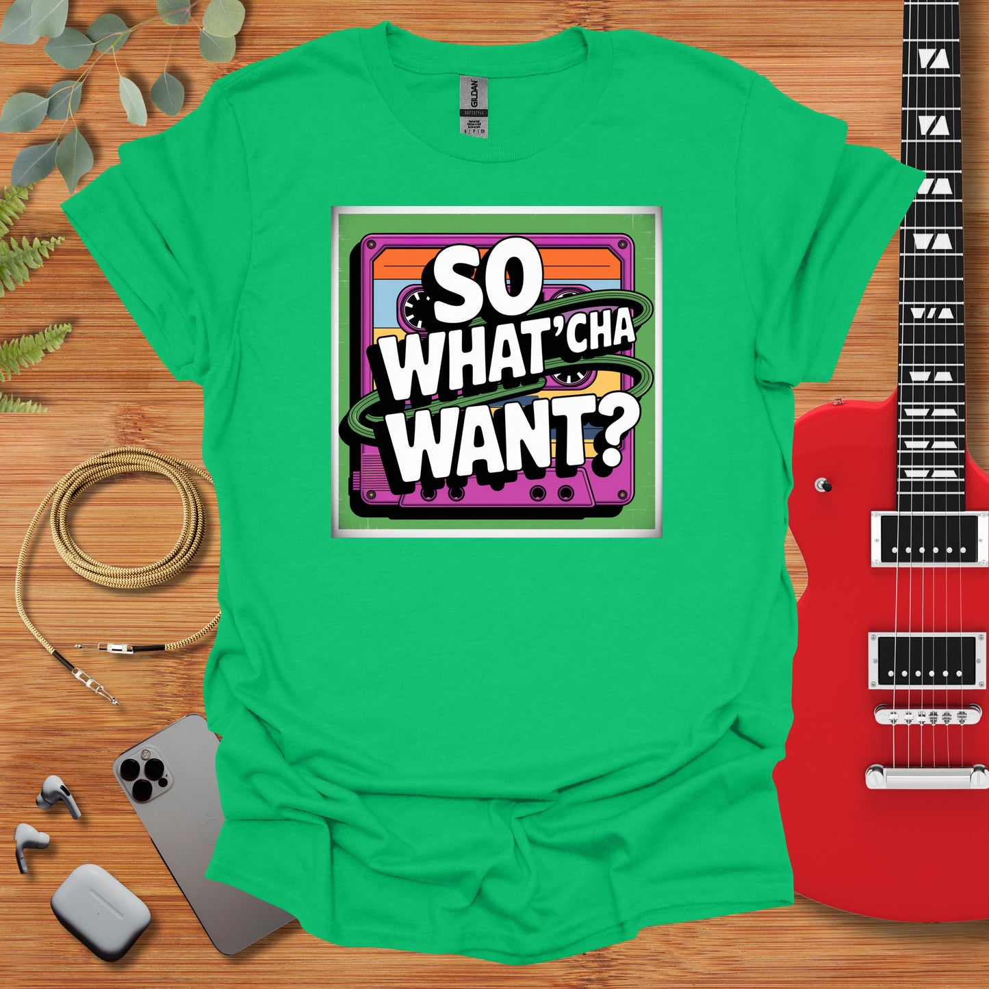 a green t - shirt that says so whatcha want? next to a guitar