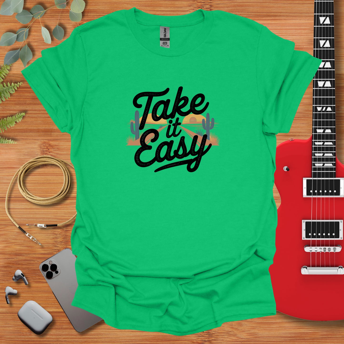 a green shirt that says take it easy next to a guitar