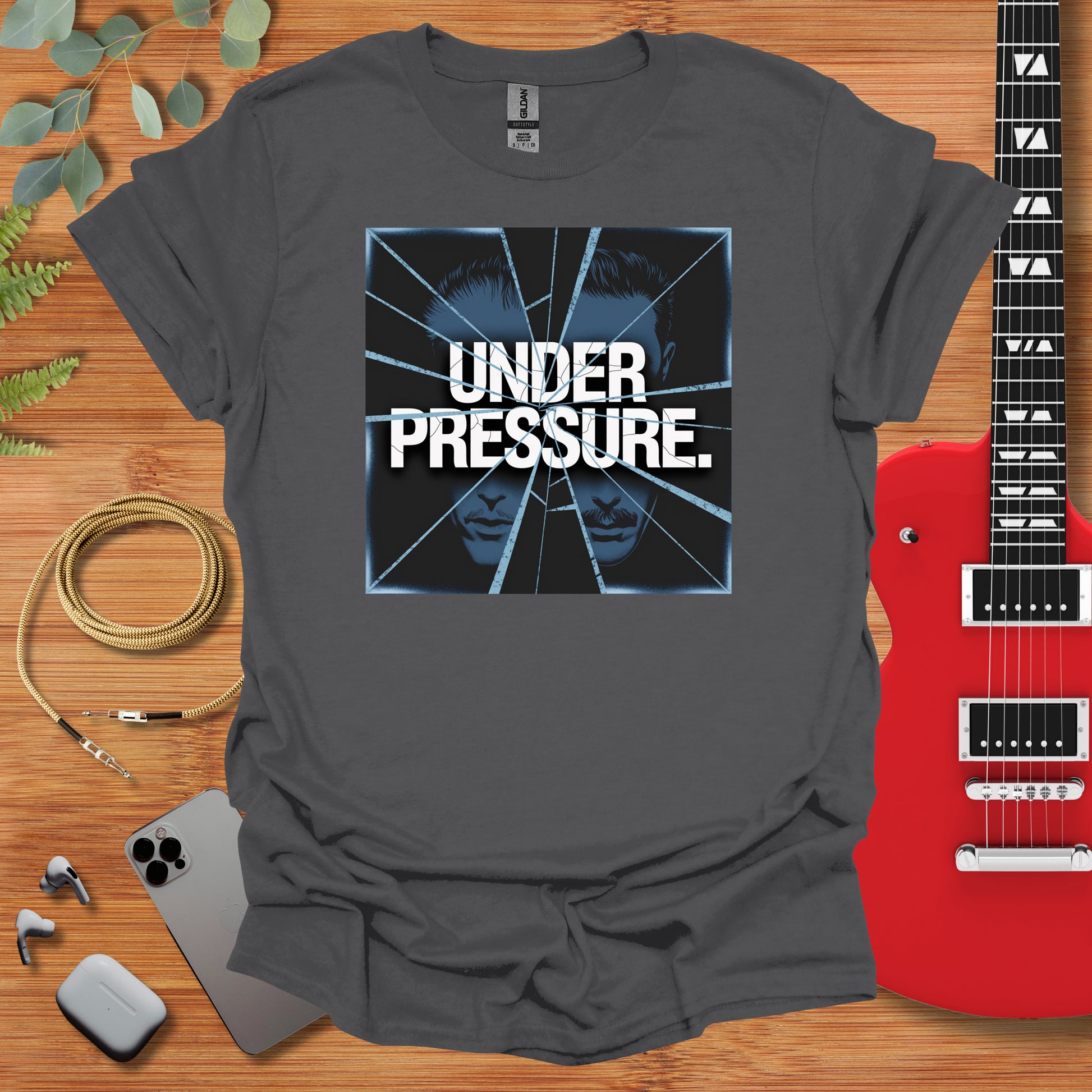 a t - shirt that reads under pressure next to a guitar