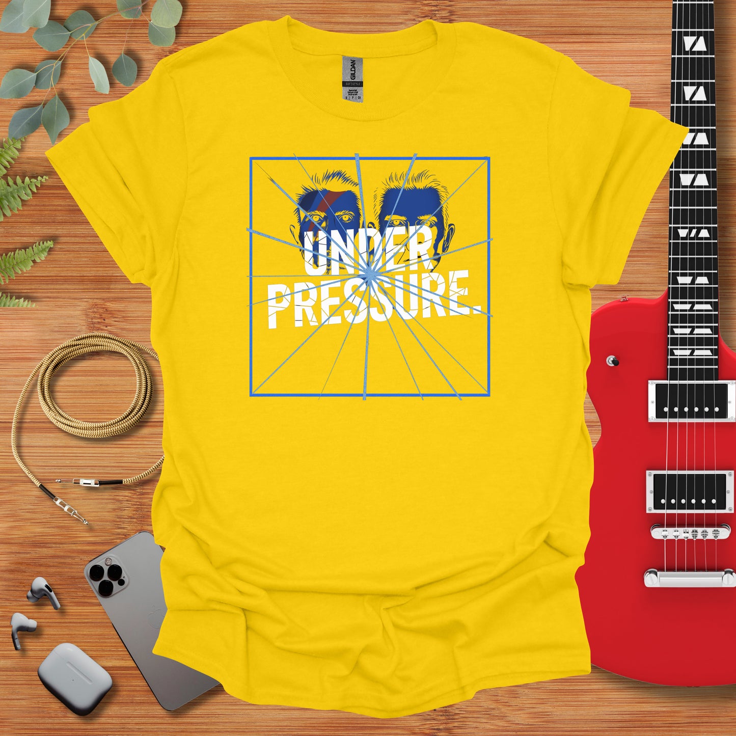 a t - shirt that says under pressure next to a guitar