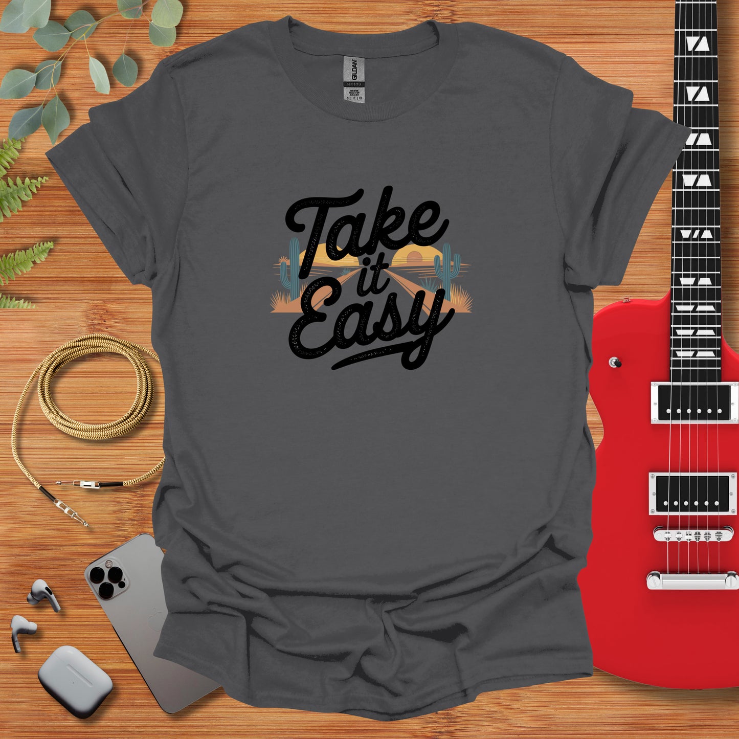 a t - shirt that says take it easy next to a guitar