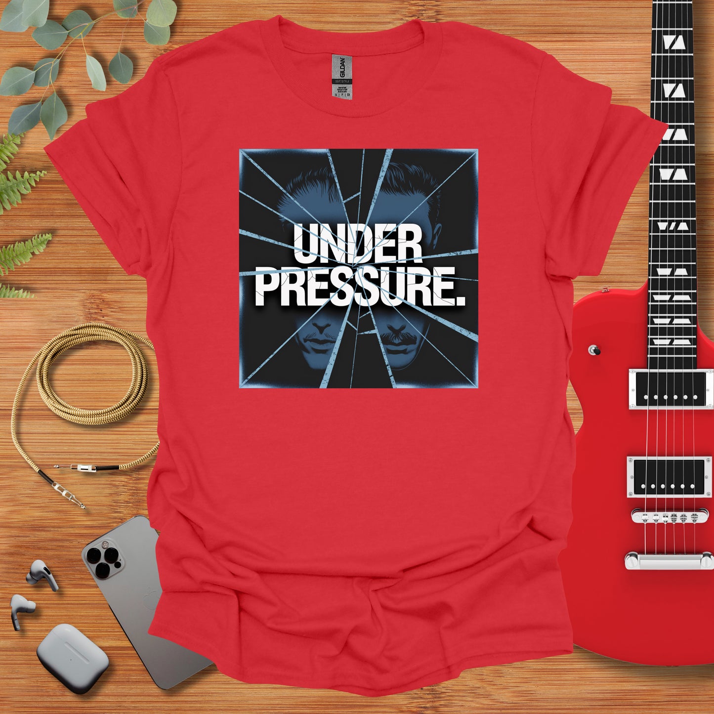 a red shirt with the words under pressure on it next to a guitar