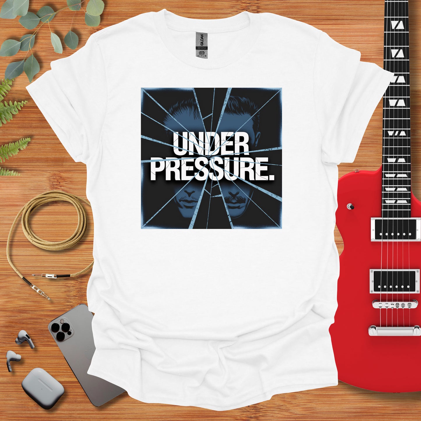 a white t - shirt with the words under pressure on it next to a guitar