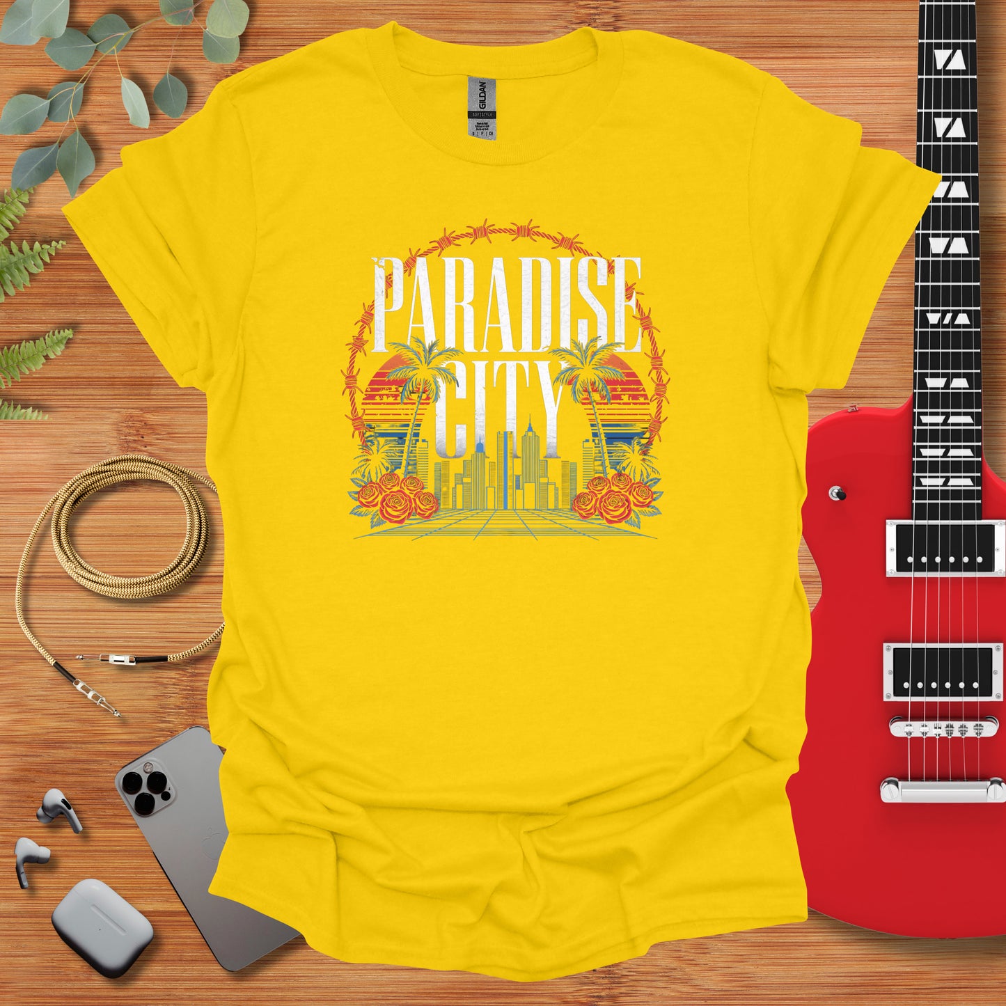 a yellow t - shirt with the phrase paradise city on it next to a guitar