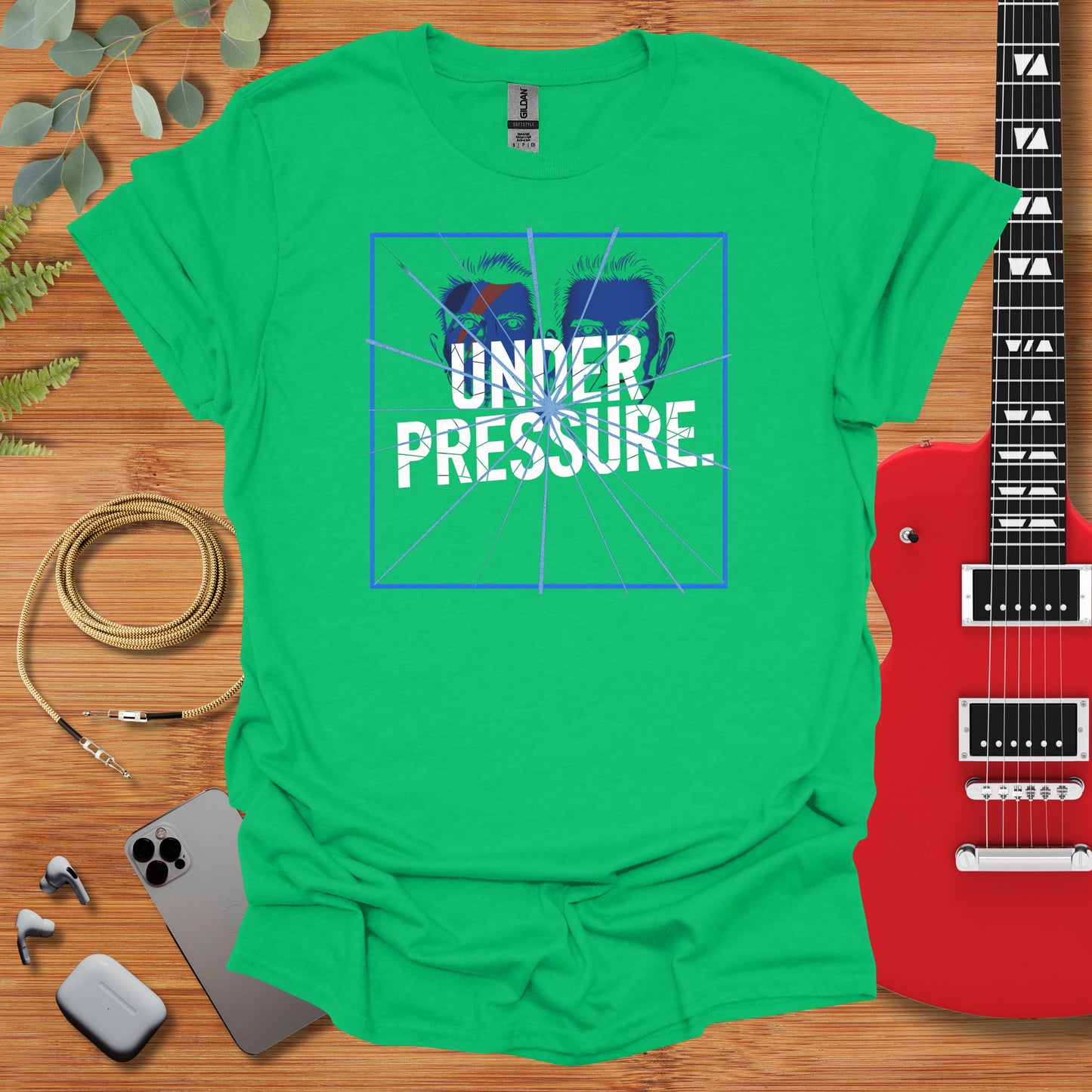 a green shirt with the words under pressure next to a guitar