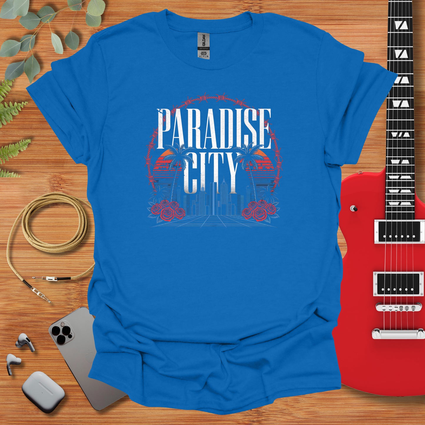 a t - shirt that says paradise city next to a guitar