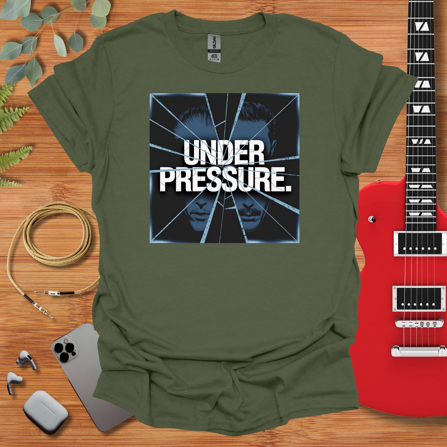 a t - shirt with the words under pressure on it next to a guitar