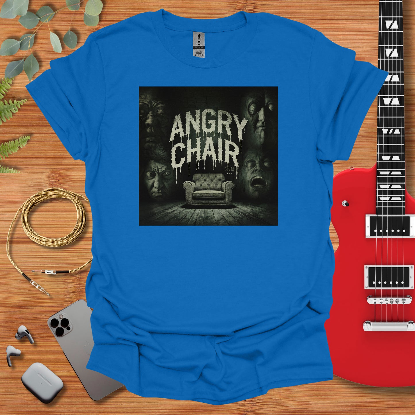 a blue t - shirt with the words angry chair on it next to a guitar