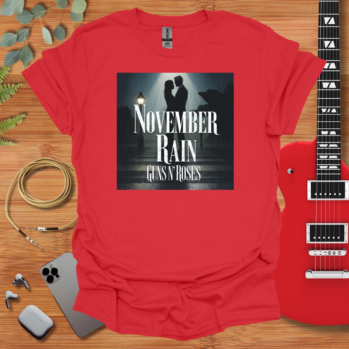 a red t - shirt with the words november rain on it next to a guitar