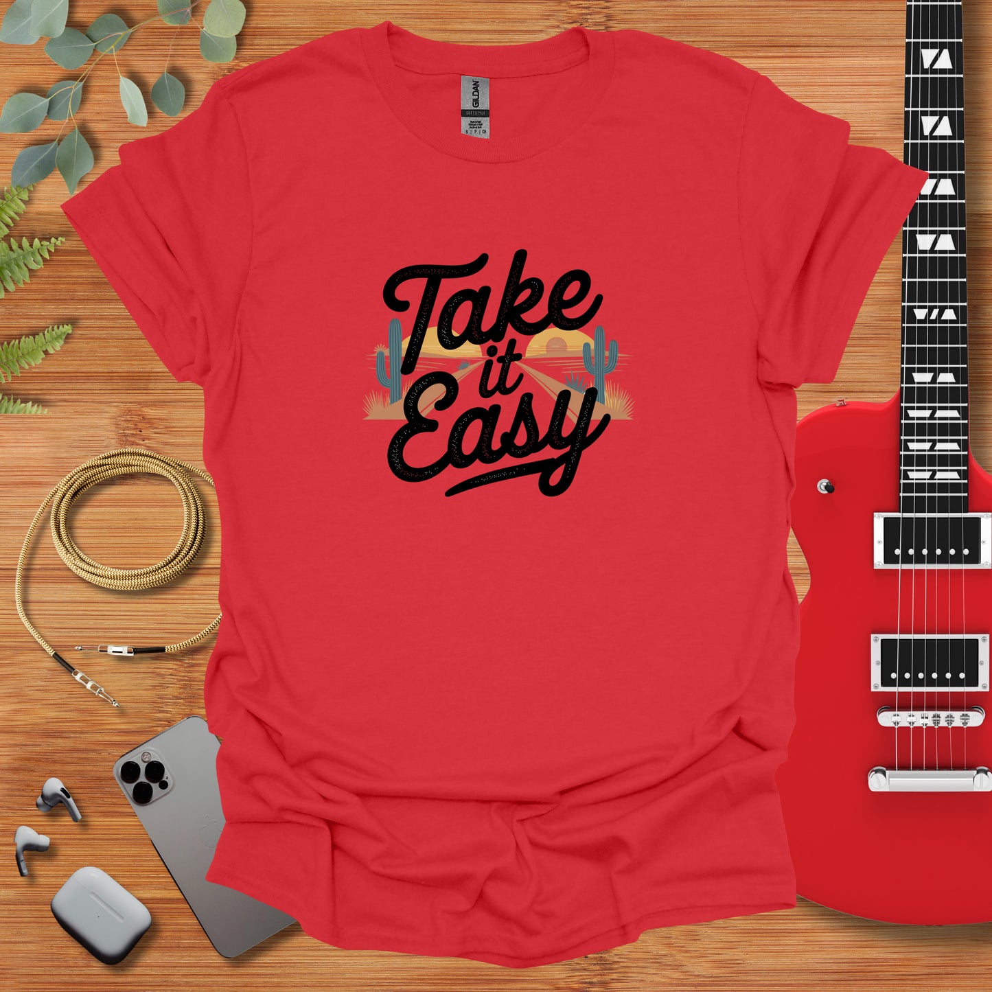 a red shirt that says take it easy next to a guitar